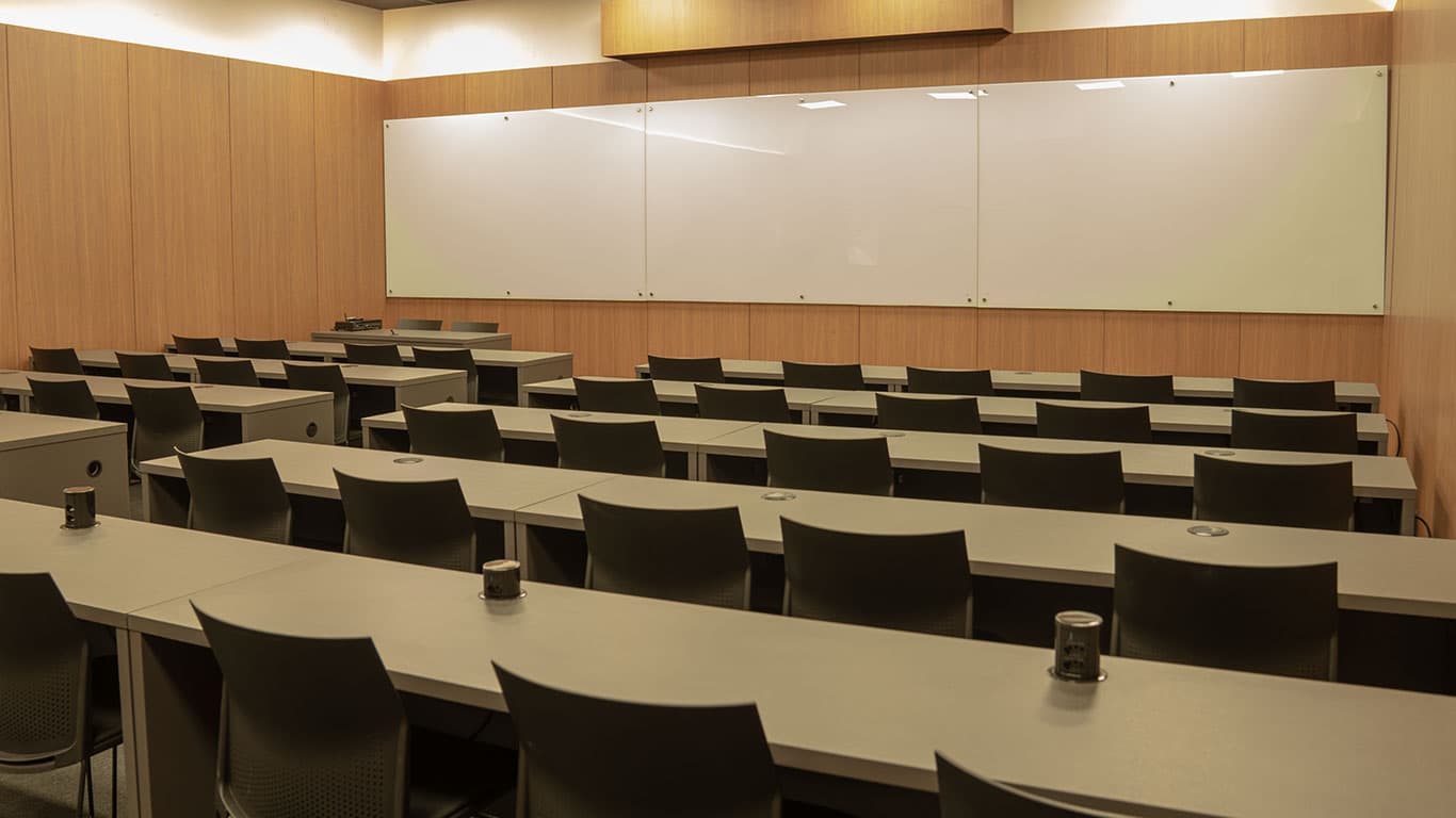 Mesas e cadeiras do auditório diante do quadro